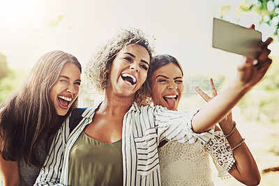 Buy stock photo Shot of a group of friends taking a selfie together outdoors