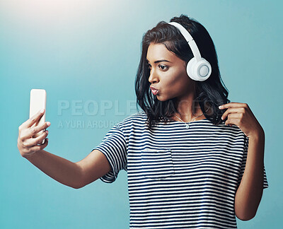 Buy stock photo Fashion, music and selfie of woman in studio for social media isolated on blue background. Photography, headphones and Indian girl in casual clothes or influencer listening to kpop on mockup space