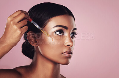 Buy stock photo Face, skincare serum and serious woman in studio isolated on a pink background mockup. Dermatology, cosmetics and Indian model with hyaluronic acid, essential oil or vitamin c dropper for skin health