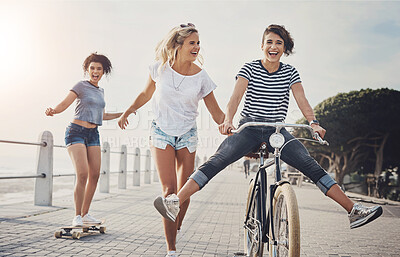 Buy stock photo Bicycle, friends and skateboard with women in summer for sports, fun and holiday break. Health, joy and wellness with cyclists riding bike on promenade for playful, Miami travel and energy together