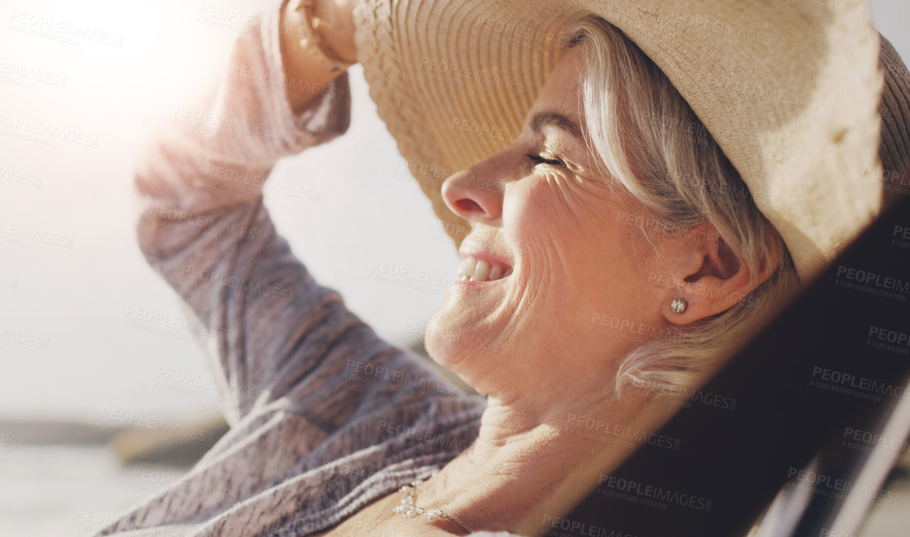 Buy stock photo Cropped shot of an attractive senior woman relaxing on a lounger on a summer's day at the beach