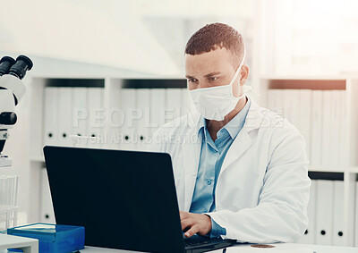 Buy stock photo Shot of a young scientist using a laptop while working on a coronavirus cure in a laboratory