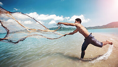 Buy stock photo Shot of a traditional thai fisherman standing in the water casting a net into the ocean