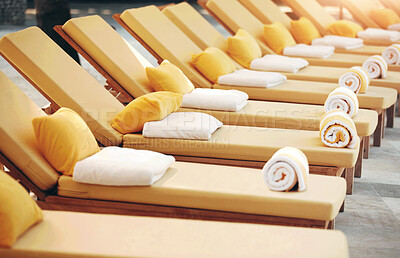 Buy stock photo Closeup row of yellow deckchairs in a line at a travel resort or hotel spa. Comfortable seating when on holiday or vacation by the pool. Towels on pillows on loungers outside poolside at a villa