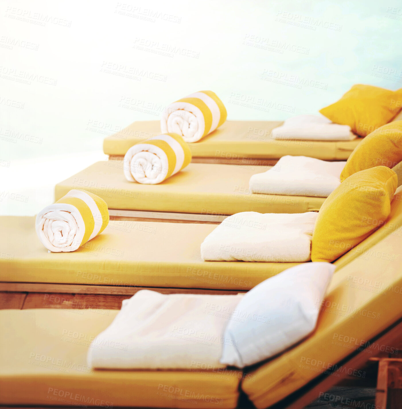 Buy stock photo Closeup row of yellow deckchairs in a line at a resort. When you need seating or a comfortable place to sit when on holiday or vacation by the pool. Towels on pillows on loungers outside at a villa