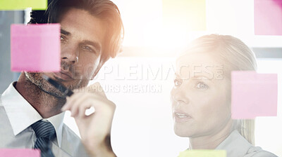 Buy stock photo A man and woman in the office looking at notes on a glass window, discussing and deciding