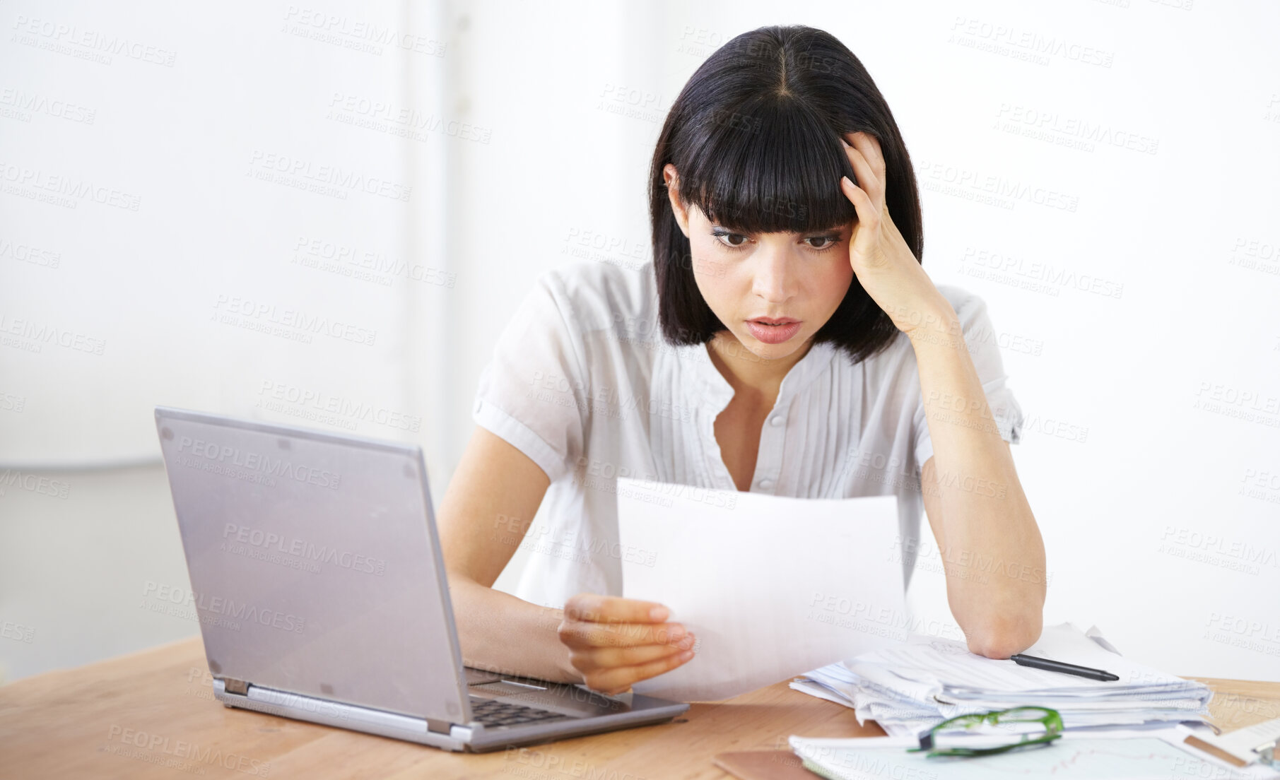 Buy stock photo A shocked businesswoman reading the financial breakdown of her budget
