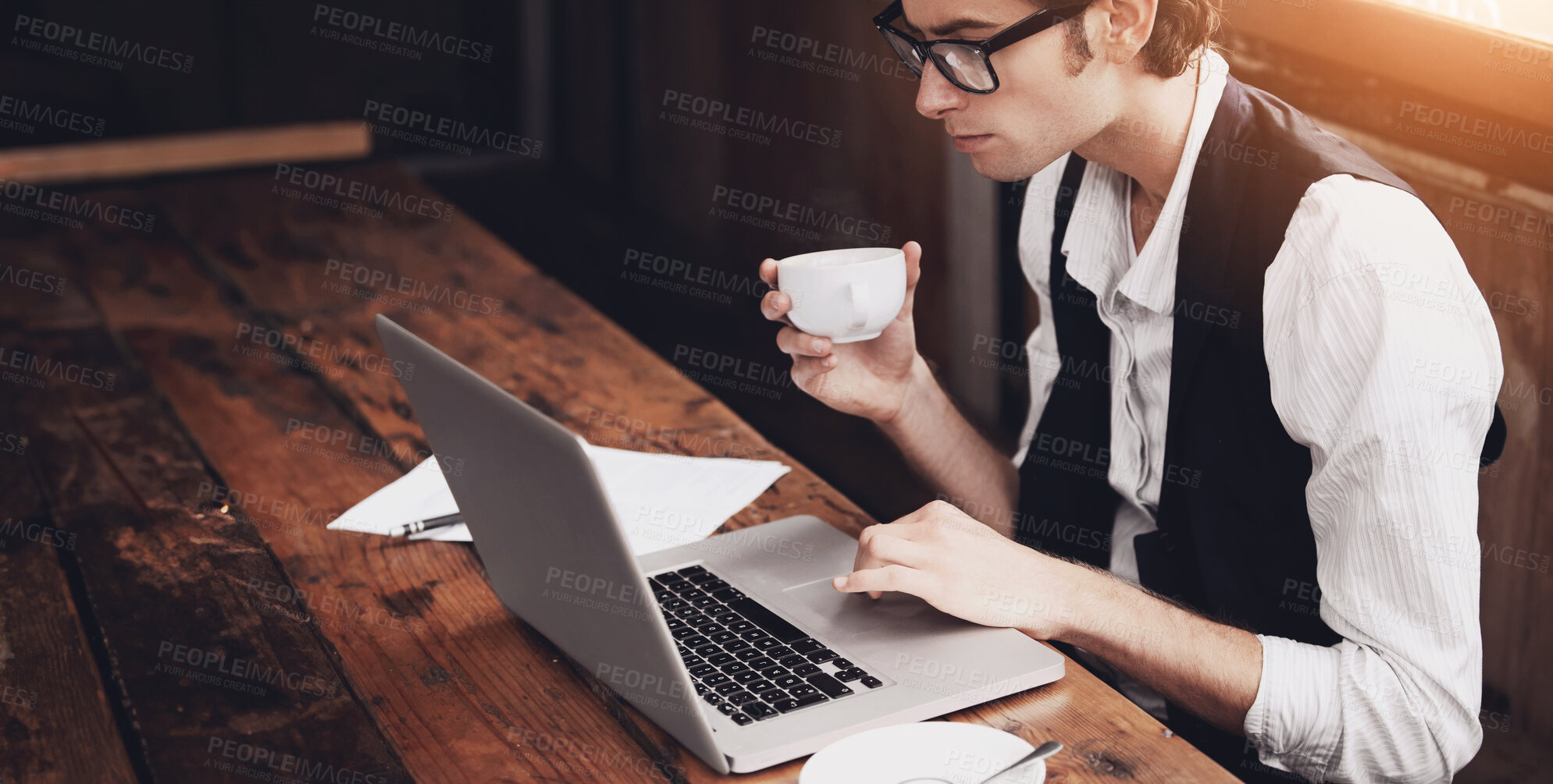 Buy stock photo Shot of a young man sitting in a cafe working on a laptop