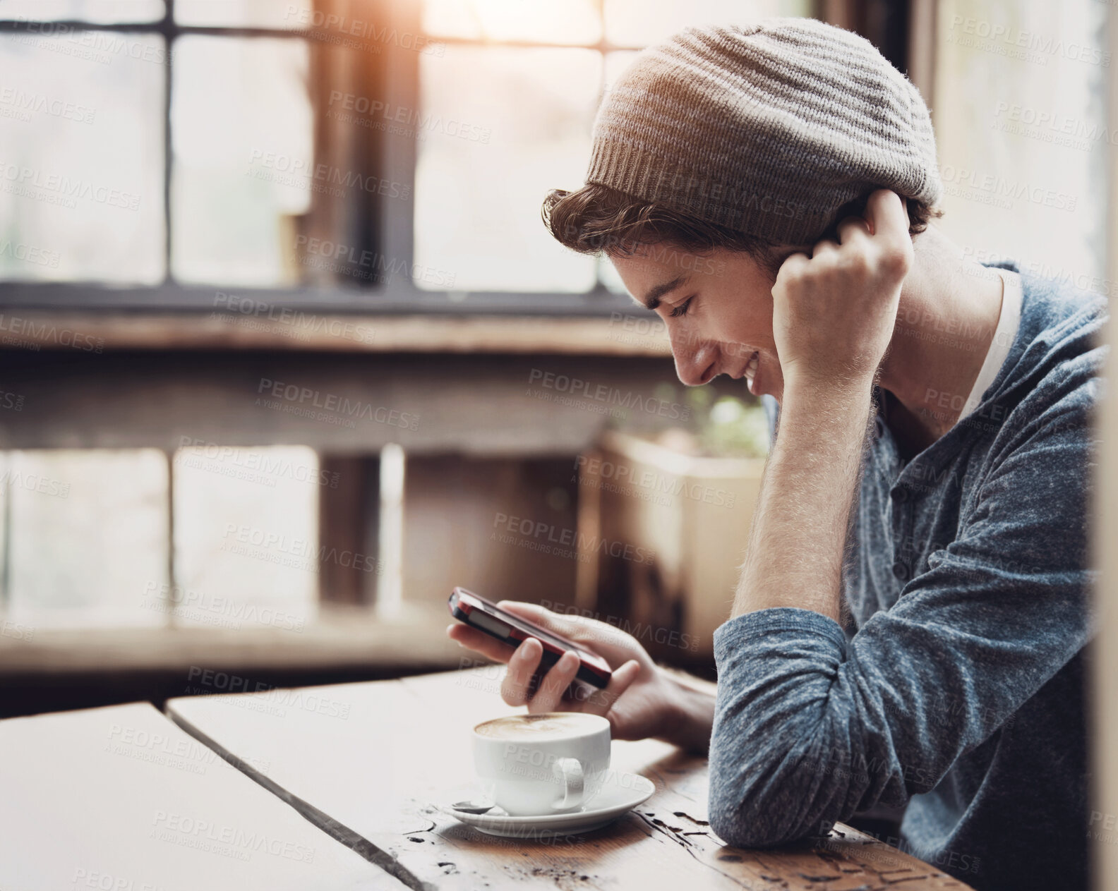 Buy stock photo Shot of young man using a cellphone while sitting in a cafe