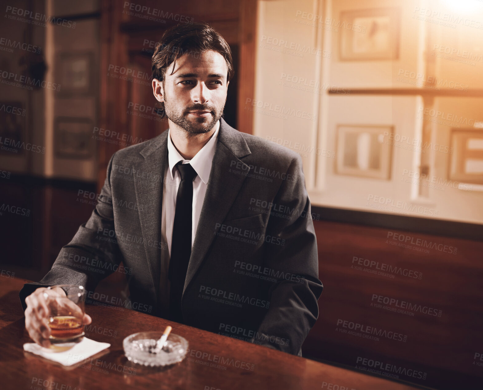 Buy stock photo A well-dressed young man sitting at a bar with a drink
