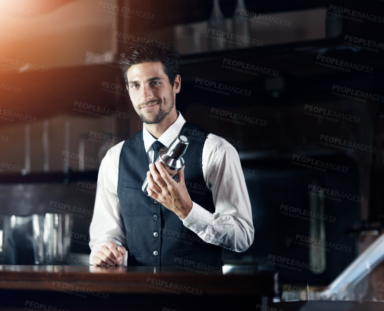 Buy stock photo Portrait of a handsome young bartender mixing a cocktail for a customer