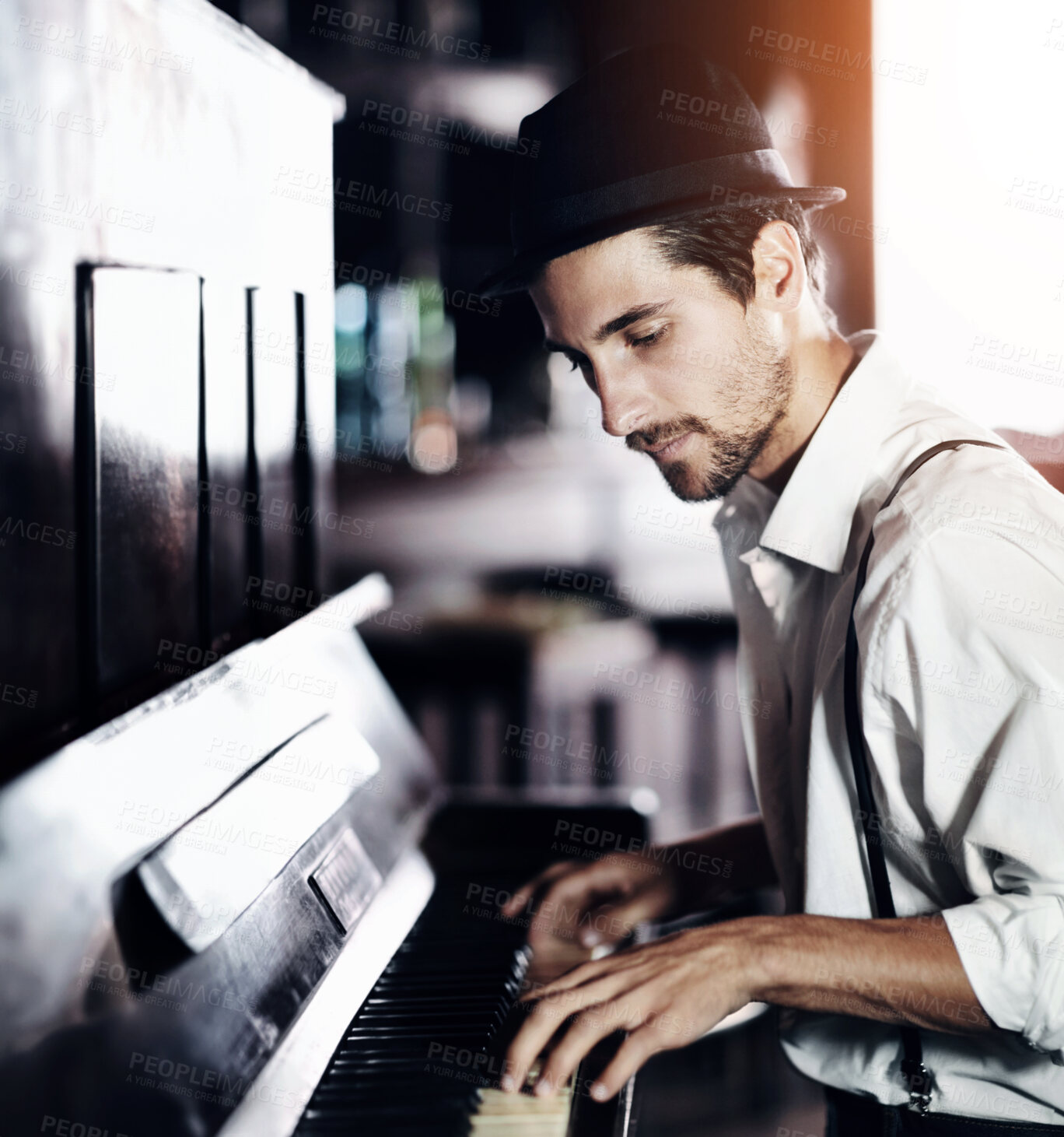 Buy stock photo A handsome young man playing the piano in a club