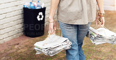 Buy stock photo Close up view of a woman recycling two stacks of old newspapers in a black bin in the backyard. Cleaning up the environment and sorting out waste and garbage to keep the ecosystem clean and healthy