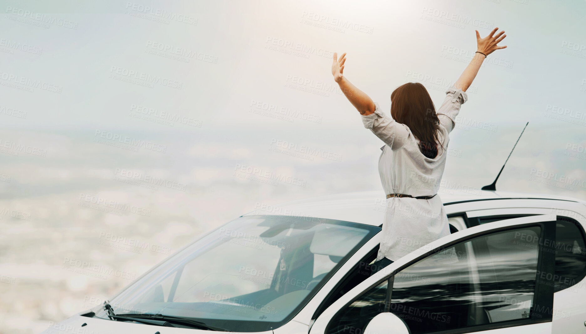 Buy stock photo Unknown woman with her arms raised while enjoying the scenic landscape during a road trip. One happy woman feeling free while traveling alone during the weekend. Exploring and adventure while driving