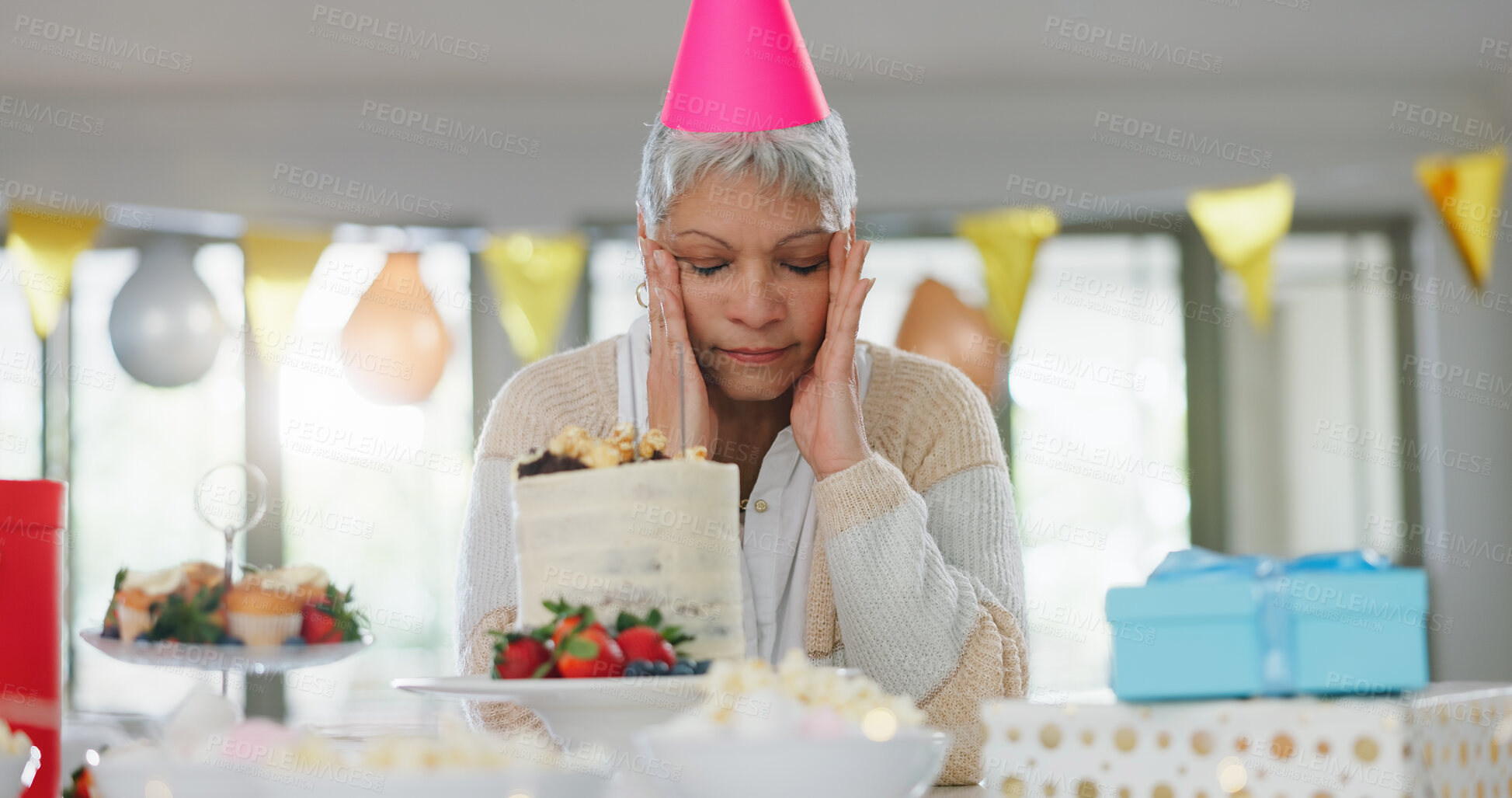 Buy stock photo Sad, birthday and senior woman in home for failed party, celebration or event alone with loneliness. Unhappy, disappointed and elderly person with cake, hat and gifts for family crisis in house.