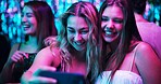 Women, selfie and happy in night club for party, celebration and excited for New Year. Girls, crowd and smile on dancefloor for photography, memory or social media post with neon lights for aesthetic