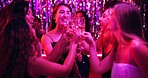 Women, cheers or glitter in night club for party, celebration and excited for New Year. Friends, champagne and energy on dancefloor for event, disco or birthday social with neon lights for aesthetic