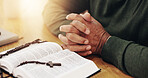 Bible, reading and hands together of person with prayer, study and spiritual education by table. Praying, learning and christian testament with worship, book and praise for healing, faith and hope