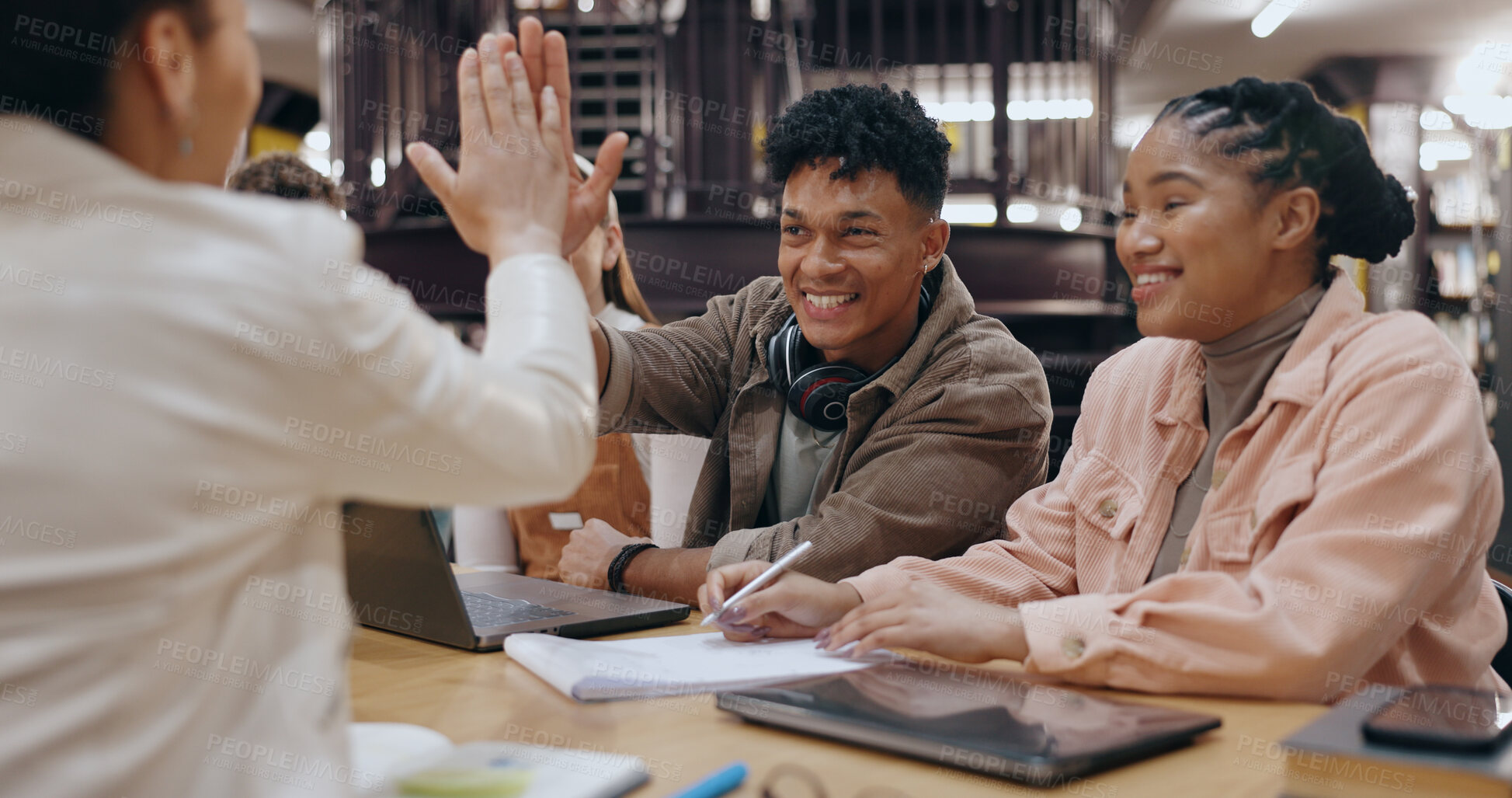 Buy stock photo Students, study group and high five in library from project success and motivation for teamwork. Education, laptop and learning on campus with happy people, smile and celebration from achievement
