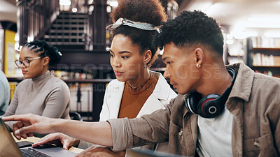 Buy stock photo Education, laptop and pointing with student friends in library of university together for learning or study. Computer, explain or growth with serious man and woman on college campus for scholarship