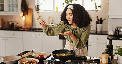 Buy stock photo Happy woman, cooking and taste with spoon in kitchen for stir fry, meal prep or flavor at home. Female person, chef and smile with organic ingredients on stove for spices, recipe or results at house