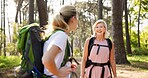 Mother, daughter and hiking in forest with talking for fitness adventure, sightseeing and explore nature. Backpack, mature woman and girl in woods with walking, holiday travel and bonding with smile