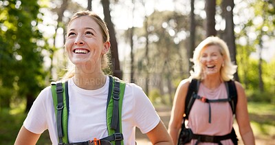 Buy stock photo Mother, daughter and walking in forest with laughing for fitness adventure, sightseeing and explore nature. Backpack, mature woman and girl in woods with hiking, holiday travel and bonding with joke