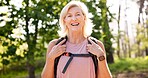 Mature, woman and hiking in forest with portrait for fitness adventure, sightseeing and explore nature. Backpack, person and happy for scenery in woods with walking, holiday travel and cardio hobby