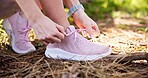 Woman, hands and tying shoes with laces for hiking or fitness in nature, forest or woods. Closeup, female person or athlete tie with sneakers or getting ready for run, trekking or outdoor exercise