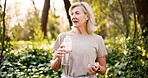 Mature woman, hiking and bottle in forest with water, rest and reflection on path with hydration in summer. Person, container and liquid for health, wellness and break with perspective in France