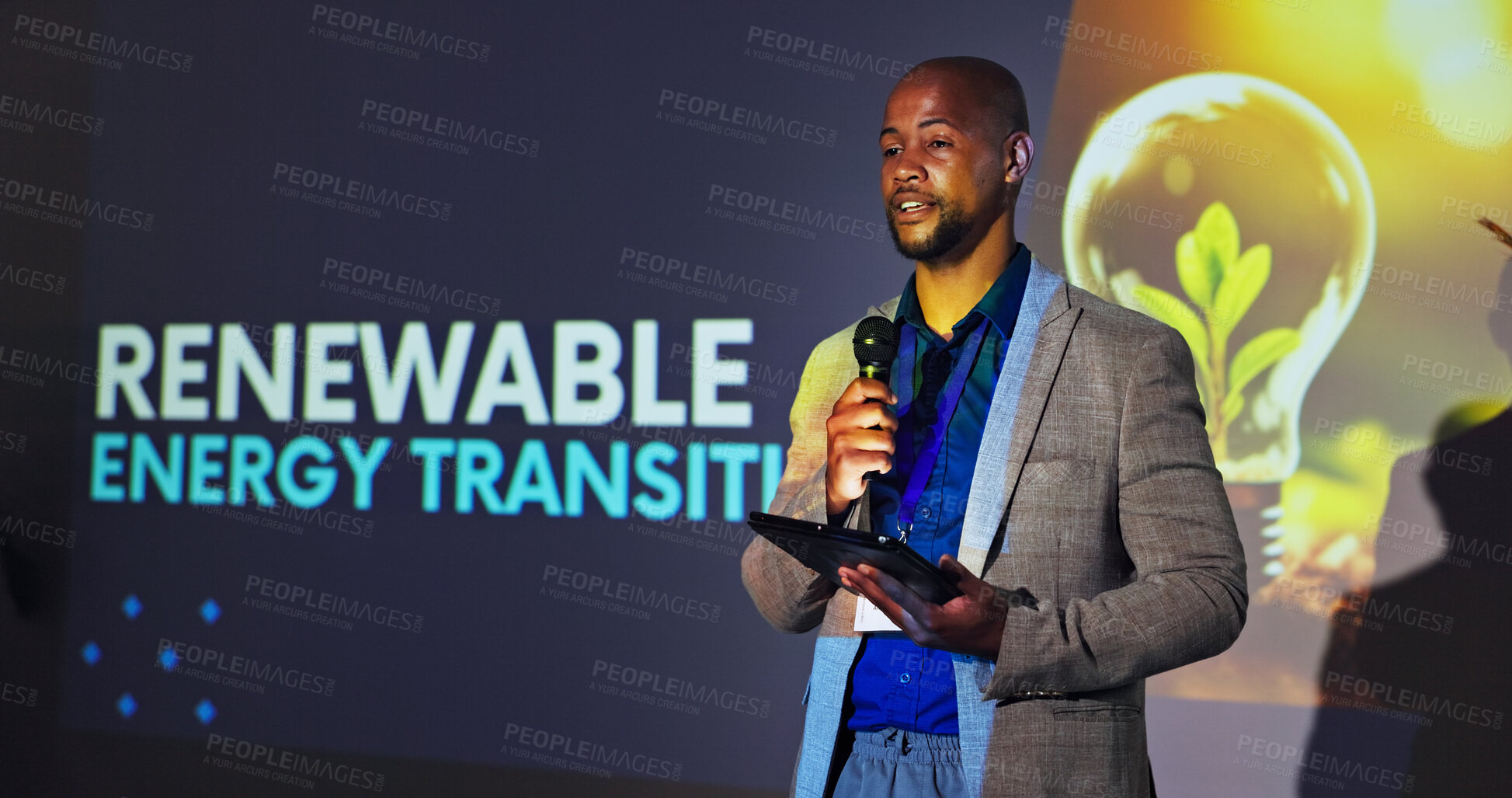 Buy stock photo Stage, presenter and black man at seminar with microphone, tablet and ideas for renewable energy. Climate change, resources and speaker at screen for conference on sustainable global power solution