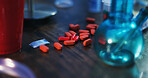 Drugs, addiction and pills on table in apartment with opioid crisis, crime and danger at night. Risk, substance abuse and illegal medicine with pharmaceutical narcotics or toxic habit in dark home