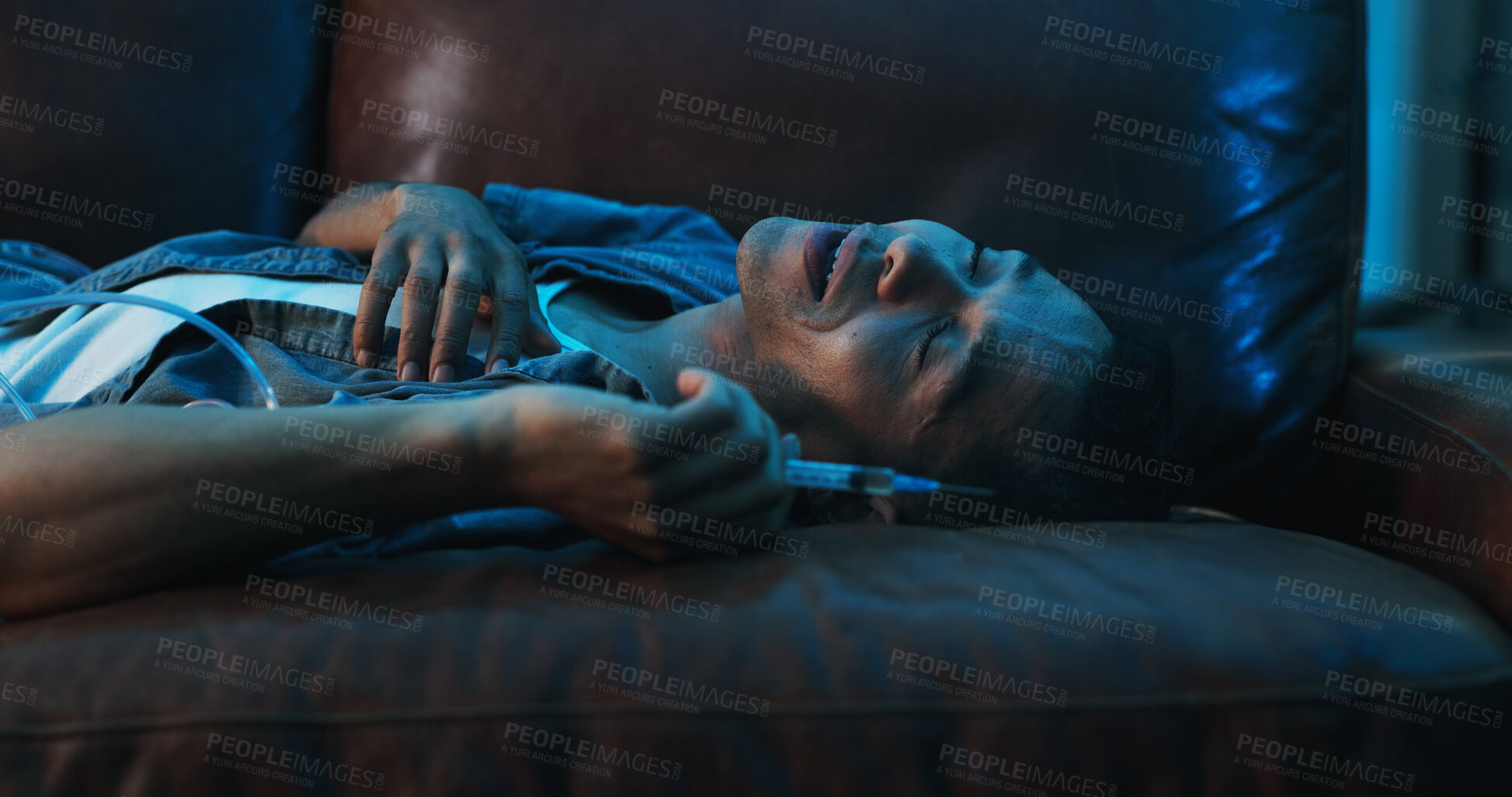 Buy stock photo Drugs, overdose and person on couch with needle, health risk and narcotic danger in apartment at night. Emergency, addiction and man on sofa with syringe, fentanyl crisis and blackout in dark home