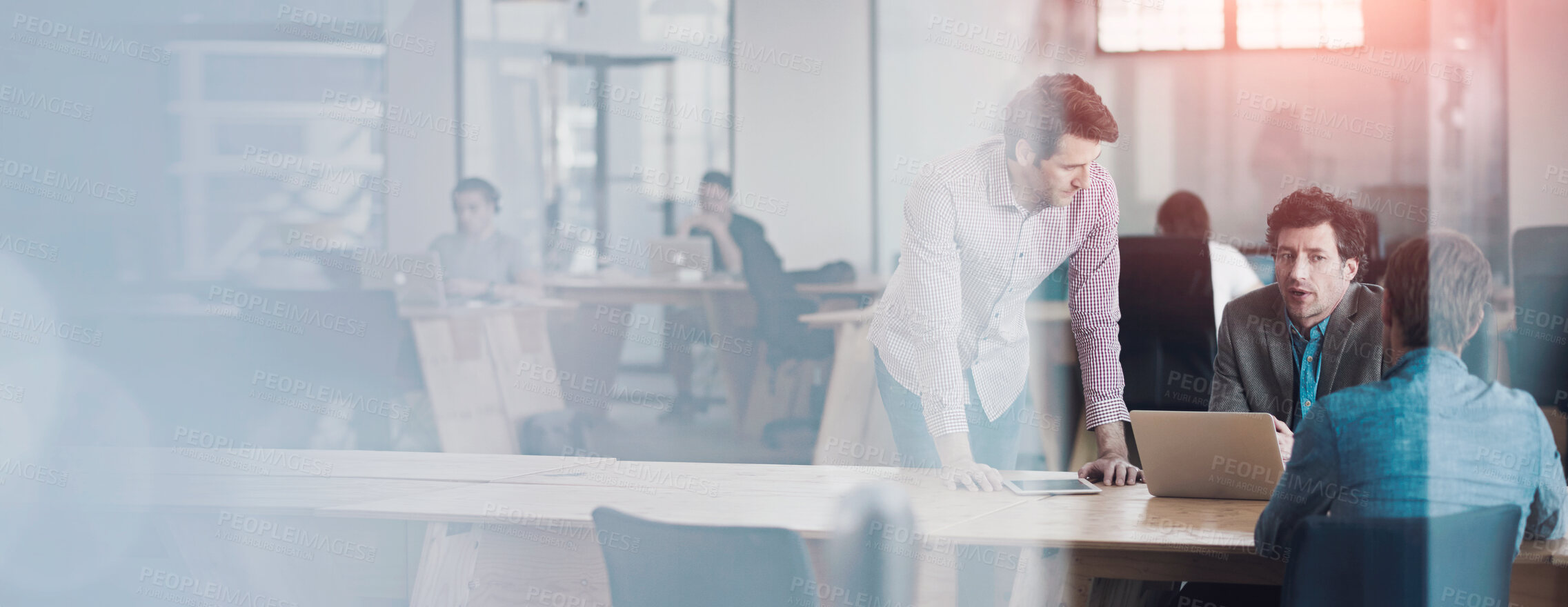 Buy stock photo Through the glass shot of a group of colleagues working together in an office