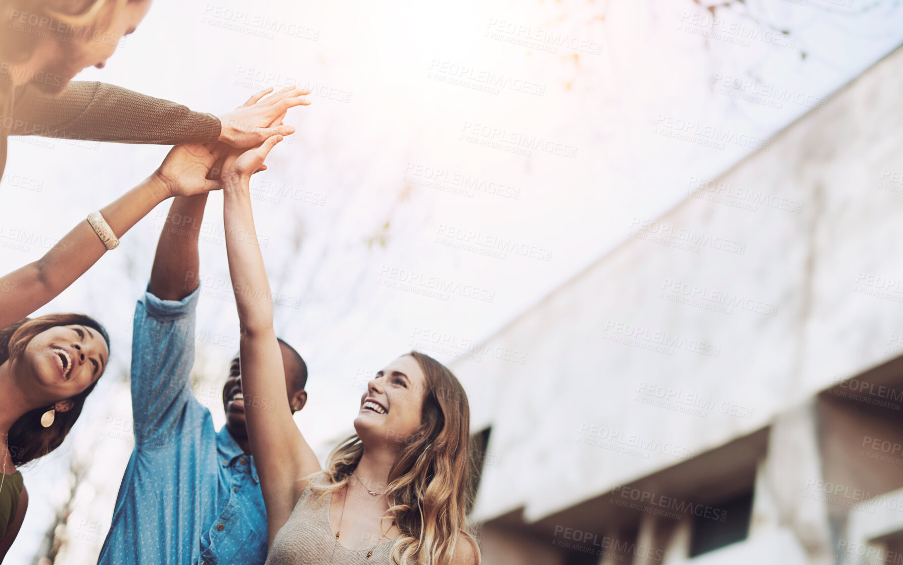 Buy stock photo Shot of a group of young friends giving each other a high five