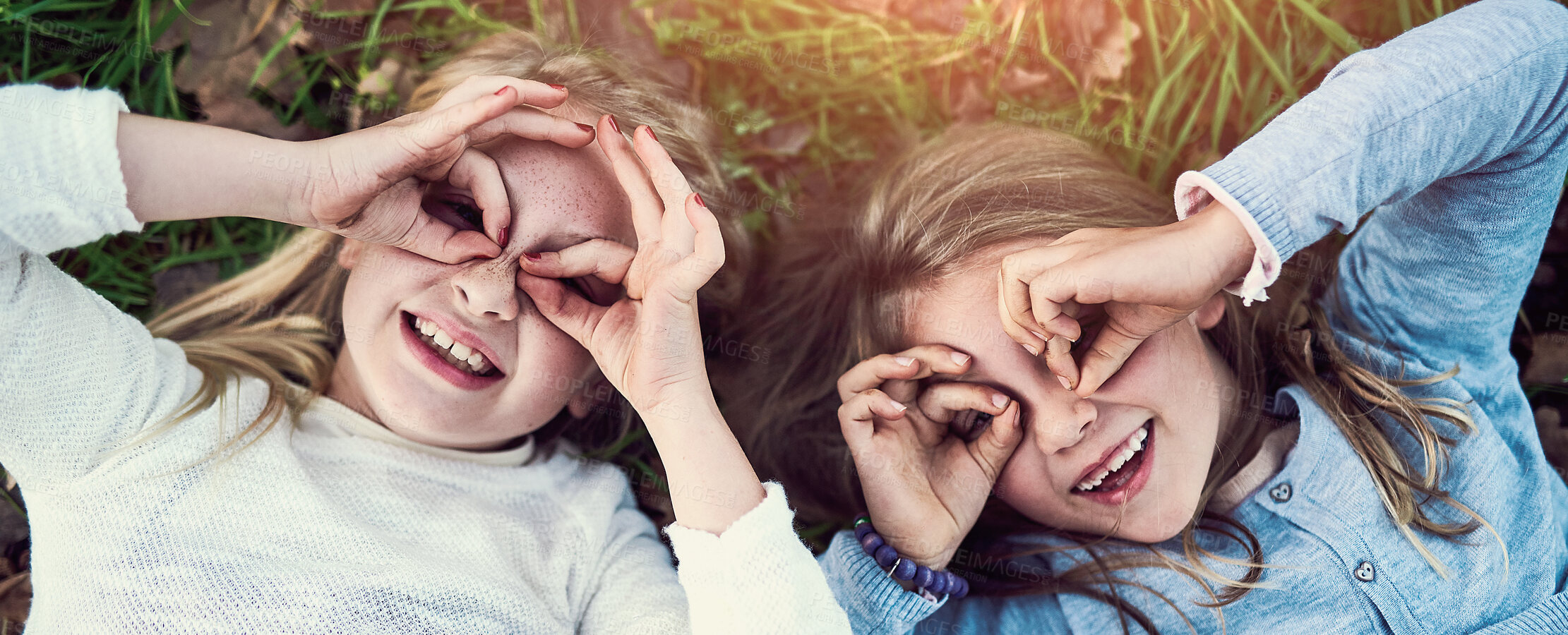 Buy stock photo Portrait of two little sisters lying on the grass outside