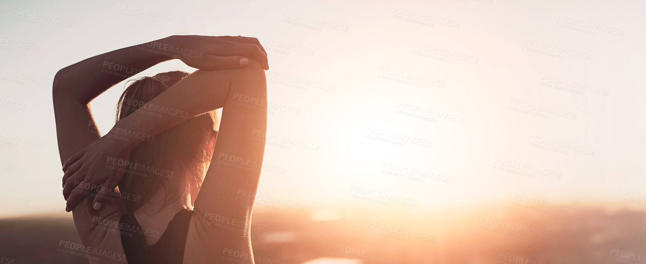 Buy stock photo Rearview shot of a sporty young woman stretching outdoors