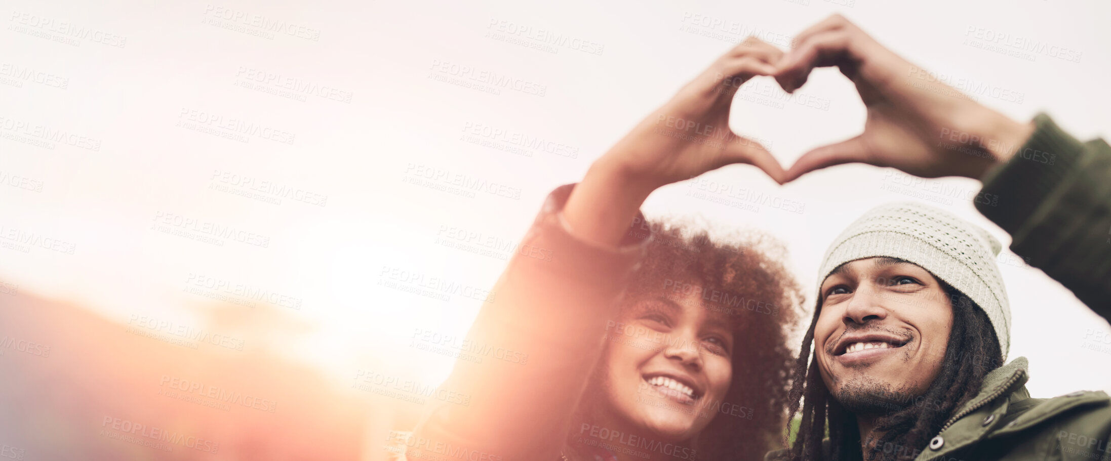 Buy stock photo Shot of two friends making a heart shape with their hands while standing outside