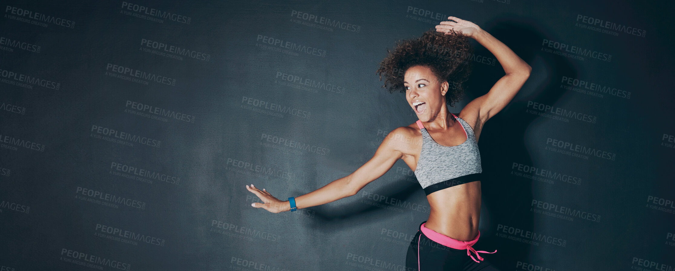 Buy stock photo Shot of a sporty young woman jumping against a grey background