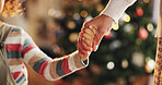 Christmas, holding hands and parents with child in home for holiday, vacation and festive season. Family, love and closeup of kid for celebration, party and tradition with decoration in living room