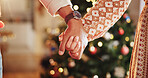 Christmas, holding hands and couple in home for holiday, vacation and festive season. Love, marriage and closeup of man and woman for celebration, party and tradition with decoration in living room