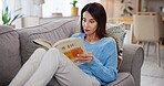 Woman, reading and book on sofa in home for story, fiction tale and literature hobby to relax. Person, fantasy novel or learning information on couch in lounge for education, knowledge or comfortable