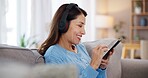 Happy, woman and phone with headphones on sofa for online, streaming and listening to audio at home. Relax, smile and female person with tech in living room for podcast, playlist and peace on weekend