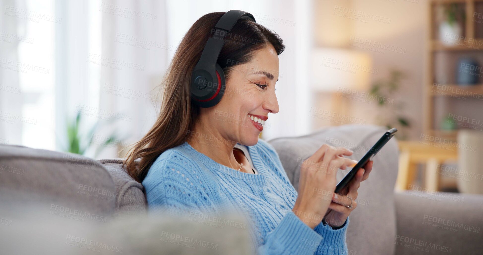 Buy stock photo Happy, woman and phone with headphones on sofa for online, streaming and listening to audio at home. Relax, smile and female person with tech in living room for podcast, playlist and peace on weekend