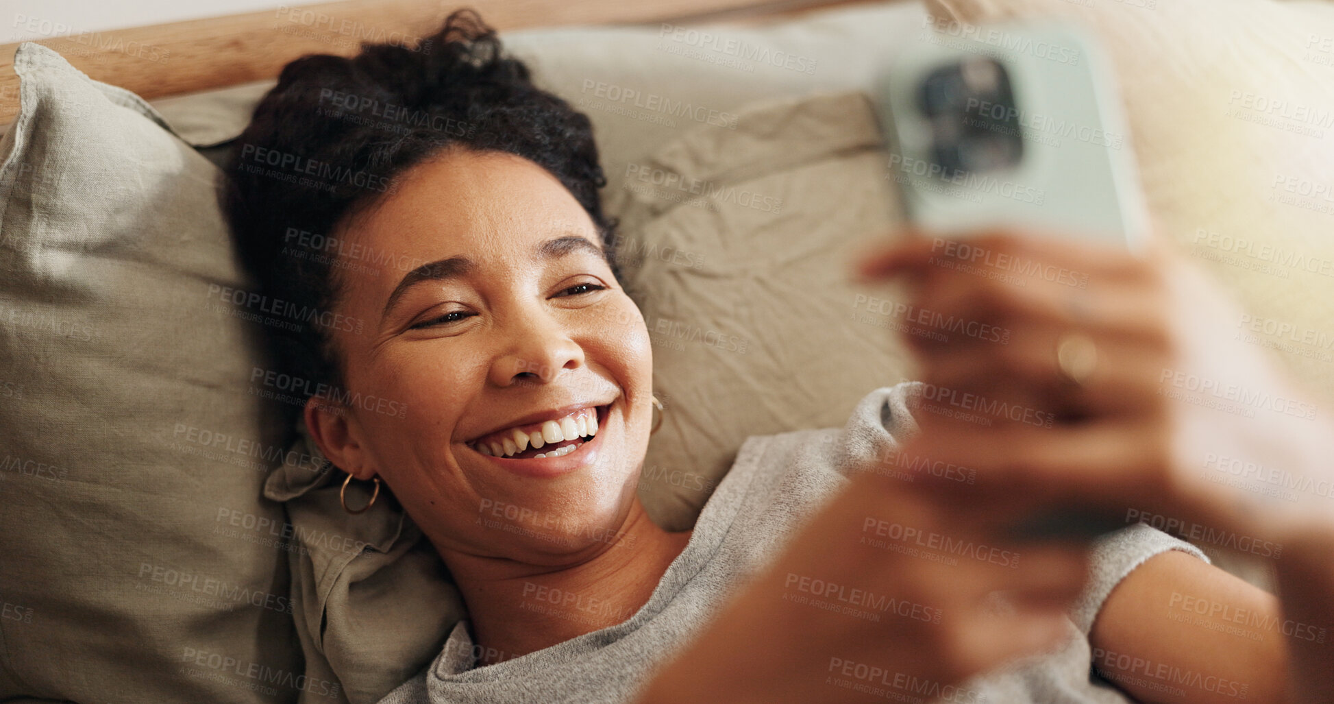 Buy stock photo Woman, laughing and phone on bed for internet surfing in home, typing message and notification. Female person, bedroom and online for communication, reading funny ebook and weekend in apartment