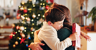 Buy stock photo Christmas, gift and hug with mother, son and bonding together with decoration, house and festive in lounge. Xmas tree, family and parent with boy, embrace and present with happiness, holiday and love