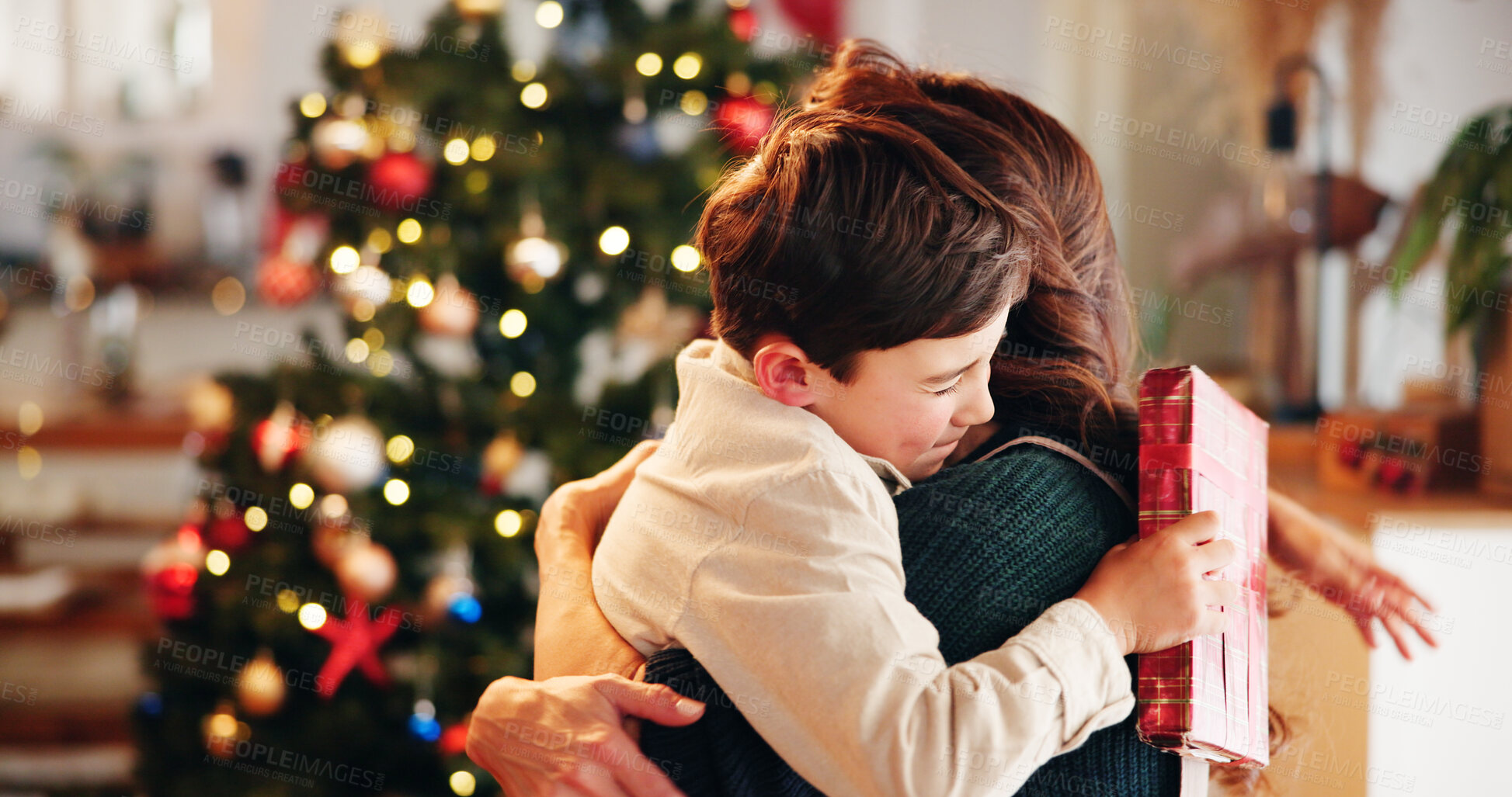 Buy stock photo Christmas, gift and hug with mother, son and bonding together with decoration, house and festive in lounge. Xmas tree, family and parent with boy, embrace and present with happiness, holiday and love