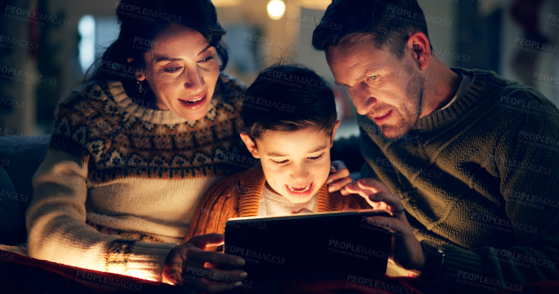 Buy stock photo Tablet, relax and child with parents in home watching movie, film or show online for entertainment. Happy, light and kid on sofa with mother and father streaming video on digital technology at night.