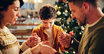 Family, prayer and holding hands in house for Christmas, solidarity and gratitude with spiritual connection. Parents, boy and worship in living room for thanks, faith and vacation as Christian people