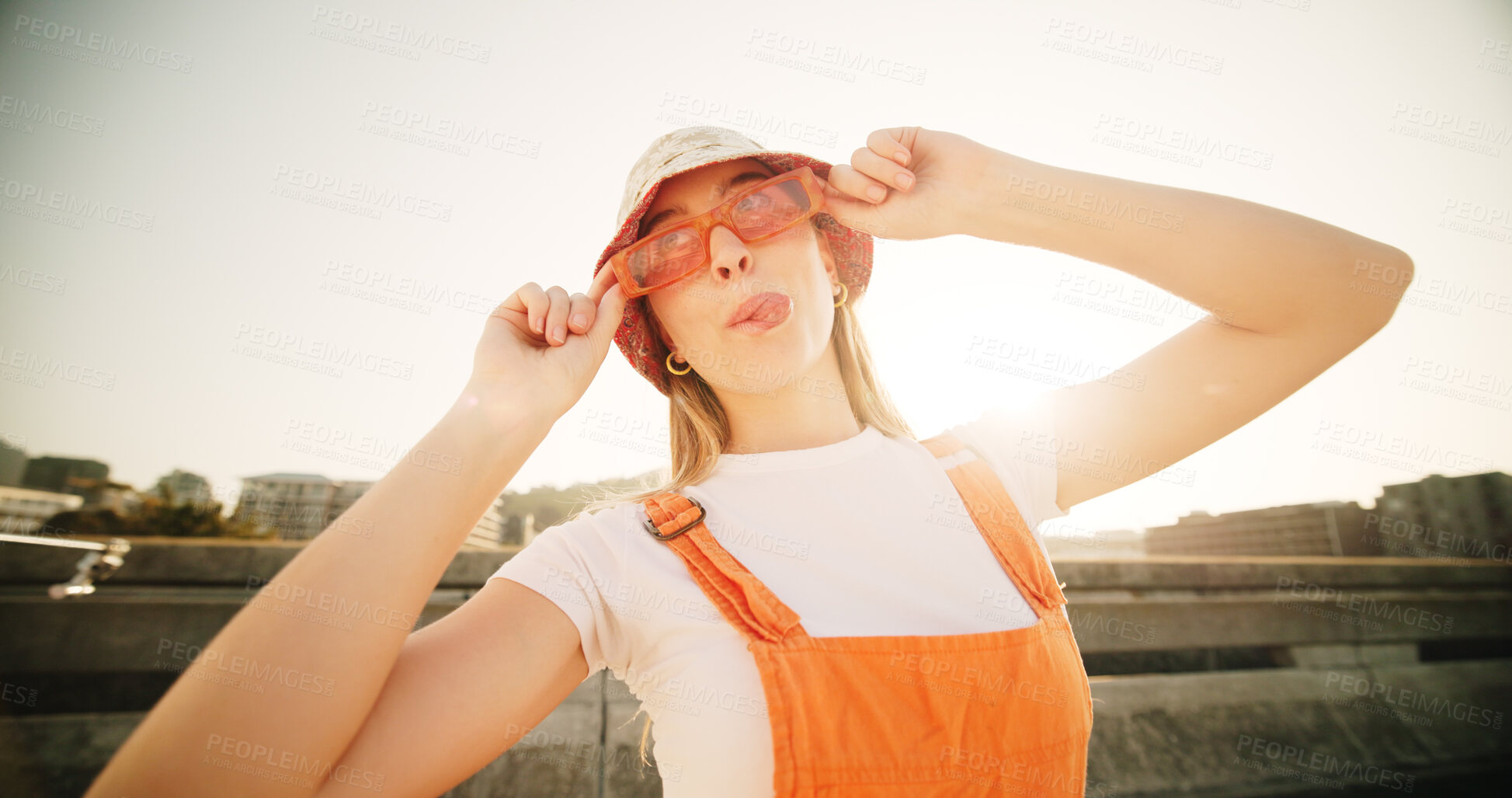 Buy stock photo Woman, sunglasses and tongue out in city with fashion, playful and funny face with style on metro bridge. Girl, glasses and hat in sunshine with joke, emoji and crazy with trendy streetwear in USA